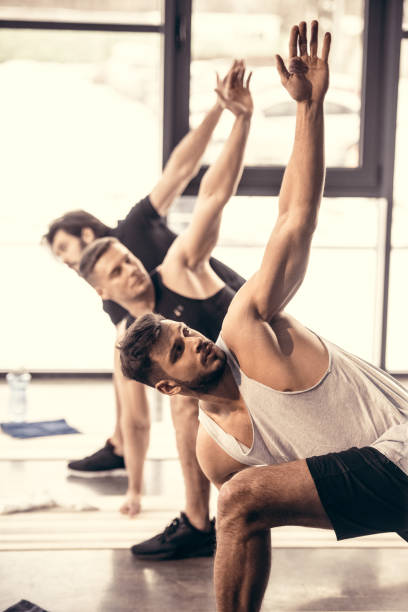 istock handsome sportsmen simultaneously exercising and stretching in gym 1010011928