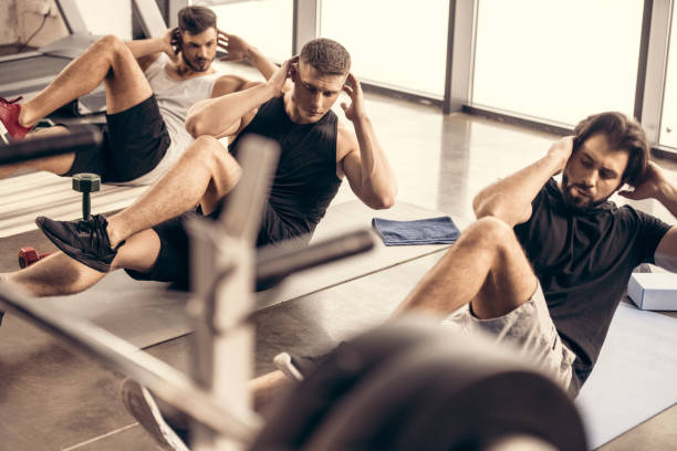 istock handsome sportive friends doing sit ups together in gym 1010018988