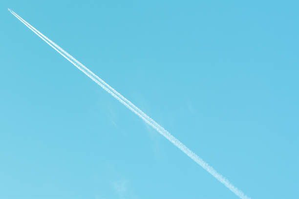 istock Low Angle View Of Airplane With Contrails Against Clear Blue Sky 1010019610