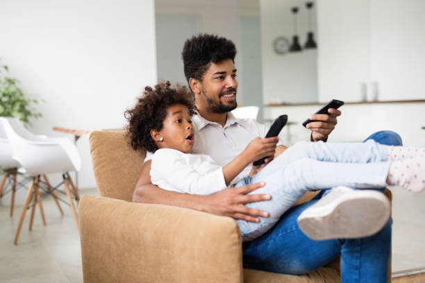 istock Father and daughter sitting on couch at home 1010022878