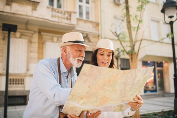 istock Tourists wearing summer hats looking at touristic map together 1010023252