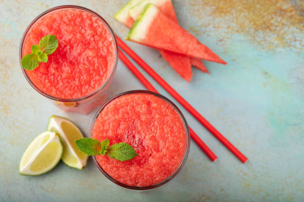 watermelon slushie with lime, summer refreshing drink in tall glasses on a blue rusty background. top view with copy space - watermelon summer melon portion imagens e fotografias de stock