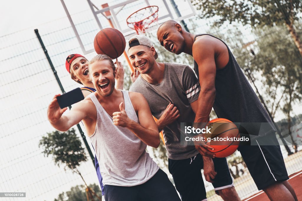 Creating happy memories. Group of young men in sports clothing taking selfie and smiling while standing outdoors Basketball - Sport Stock Photo