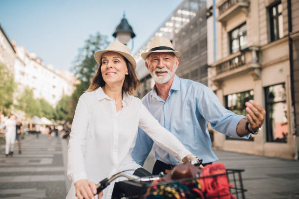 istock Older man standing behind mature woman riding a bicycle 1010035336