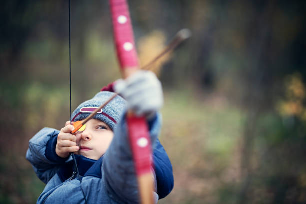 istock Little boy shooting bow in forest 1010046168