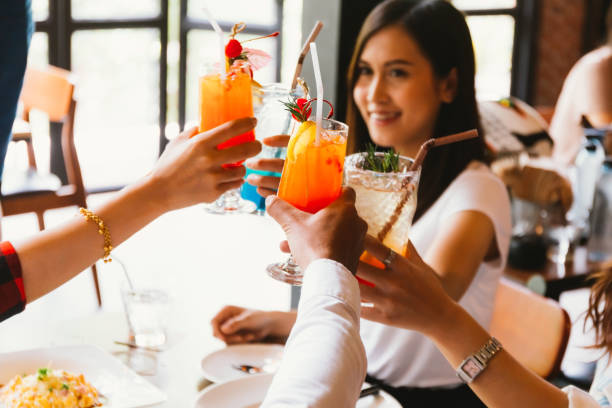mulher asiática bonita e alegre animar para o brinde e comemoração com os amigos no bar - foco em óculos. - thailand restaurant cocktail bar - fotografias e filmes do acervo