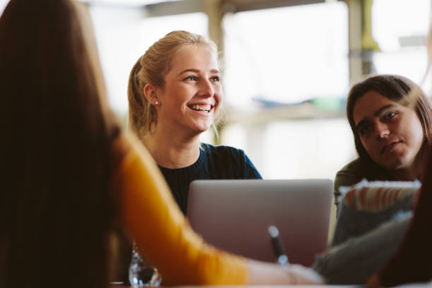 University students in classroom after lecture Female student sitting amongst classmates and smiling in lecture room. University students in classroom after lecture. youth culture stock pictures, royalty-free photos & images