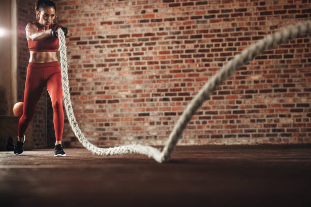 istock Tough woman exercising with battling rope 1010060150