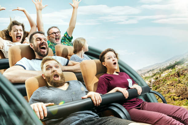 las emociones felices de los hombres y las mujeres que tienen buen tiempo en una montaña rusa en el parque - rollercoaster fotografías e imágenes de stock