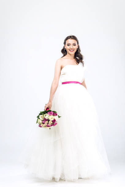 istock smiling young bride in wedding dress with bouquet on white 1010065526