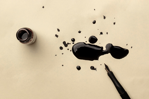 Una foto aérea de una tinta con gotas de tinta y una pluma de punta, con espacio de copia photo