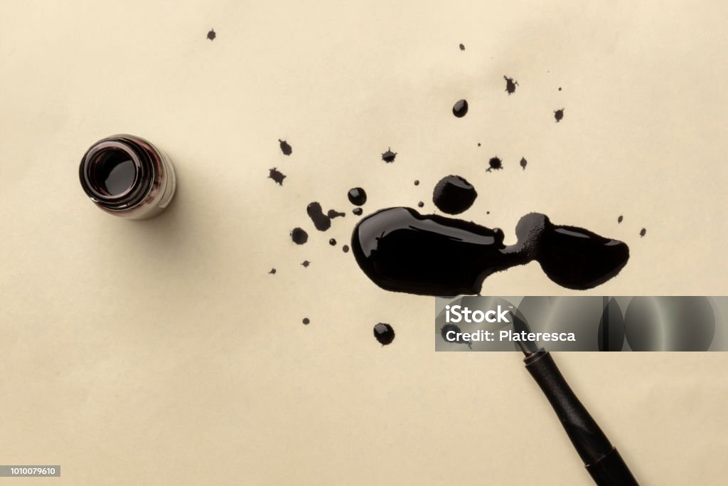 An overhead photo of an ink well with drops of ink and a nib pen, with copy space An overhead photo of an ink well with drops of ink on a textured off-white paper, with a nib pen, with copy space Ink Stock Photo