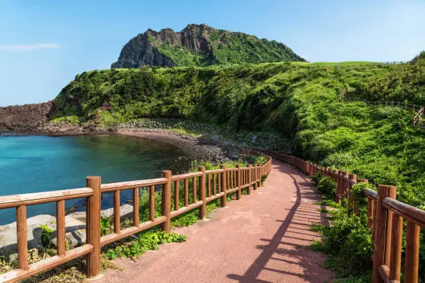 Pathway leading to beach with view over ocean and and volcano crater Ilchulbong, Seongsan, Jeju Island, South Korea