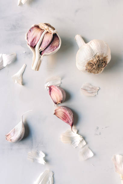 Garlic bulbs on a white table Garlic cloves and bulbs on a white table papery stock pictures, royalty-free photos & images