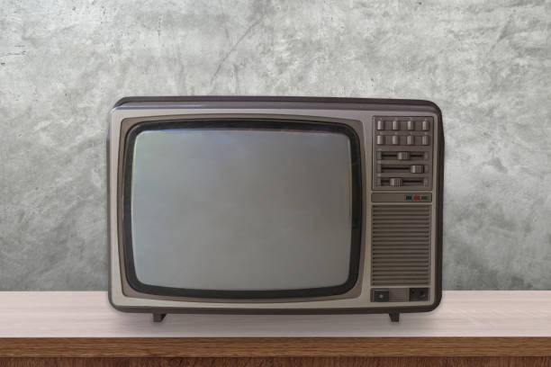istock Vintage TV box on wooden table and cement wall background. 1010093558