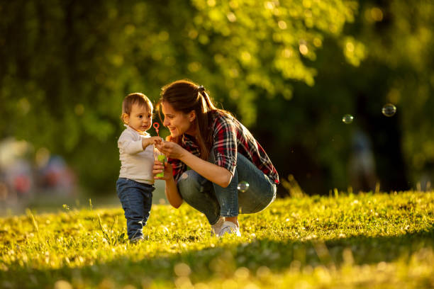 istock Mother and baby blowing bubbles in the park 1010105328