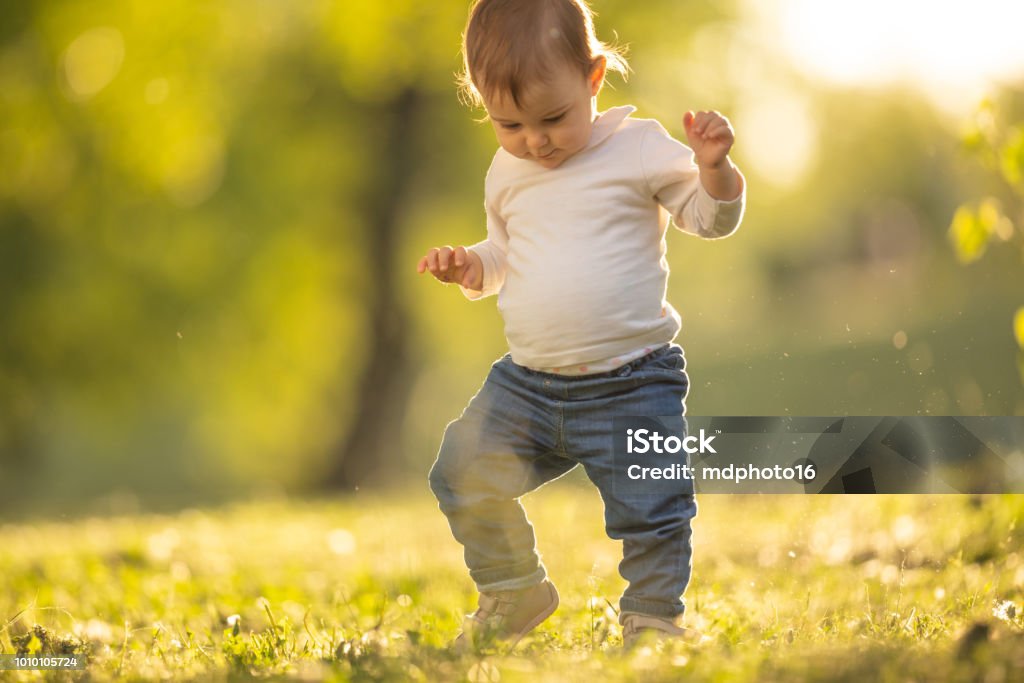 Baby girl taking her first steps in a park - Royalty-free Andar Foto de stock Baby girl taking her first steps in a park - Royalty-free Andar Foto de stock