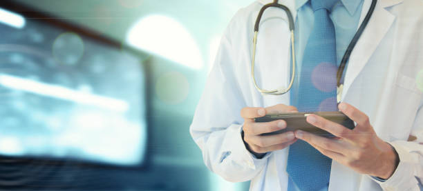 istock Doctor hands with mobile phone. Male doctor in white coat is using a modern smartphone device with touch screen. 1010106052