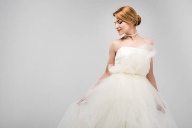 istock attractive bride posing in white wedding dress, isolated on grey 1010106300