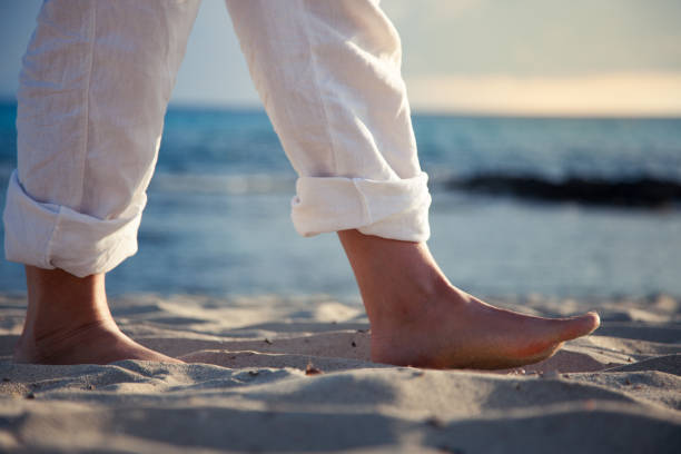 pies de hombres a pie descalzo sobre la arena de la playa al amanecer - barefoot behavior toned image close up fotografías e imágenes de stock