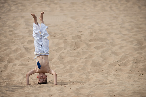 Boy practicing capoeira, brazilian martial art that combines elements of dance, acrobatics and music, handstand