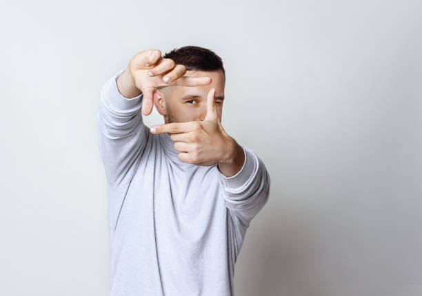 hübscher junger mann mit schwerpunkt mit fingern, gestaltung mit den händen auf grauem hintergrund, raum kopieren. portrait mann in weißen rollkragenpullover streckte seine hände in einer geste, rahmung hautnah. - fingerrahmen stock-fotos und bilder