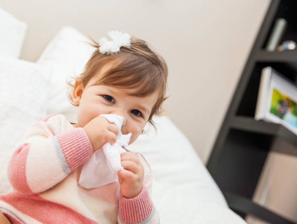 Little Girl Wiping Her Nose with a Tissue stock photo