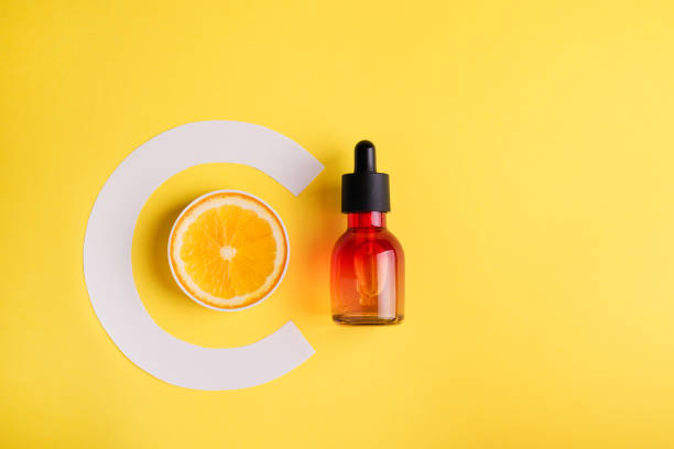 Glass bottle and orange on a yellow background. Organic bio cosmetics with vitamin C. The concept of Minimalism Flat lay. vitamin c stock pictures, royalty-free photos & images