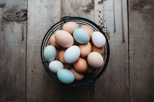 Multi-colored organic eggs from free range chickens on a rustic barn wood background.  Multi-colored organic eggs from free range chickens on a rustic barn wood background.  A brown, white, and a baby blue egg in a row.