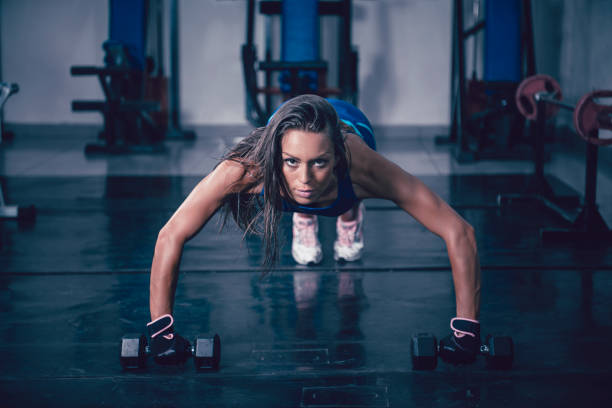 istock Athletic Female Doing Pushups With Dumbbells In Gym 1010146000