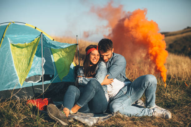 istock Young happy couple holding smoke bombs on camping 1010151810