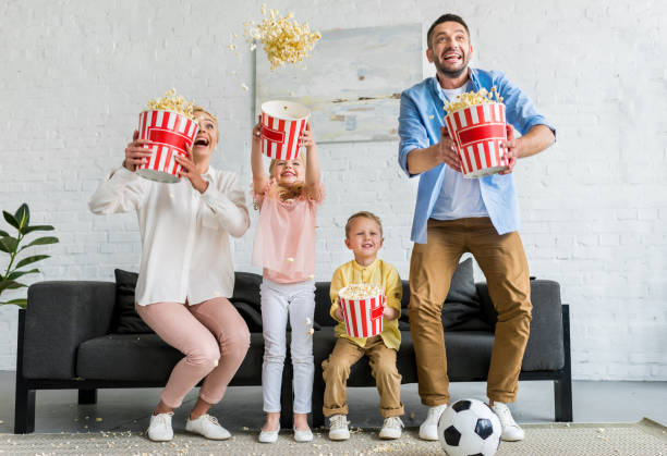 istock excited family holding boxes and throwing popcorn at home 1010159654