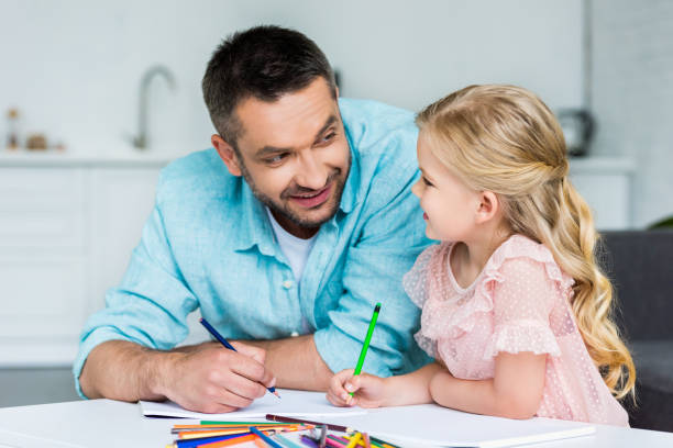 istock happy father and daughter smiling each other while drawing together at home 1010160824
