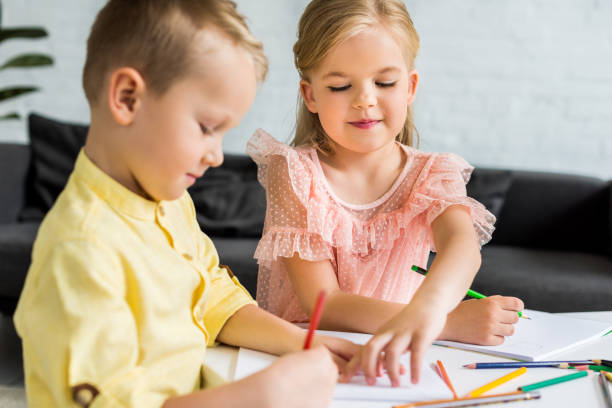 istock adorable siblings drawing with colored pencils at home 1010160946