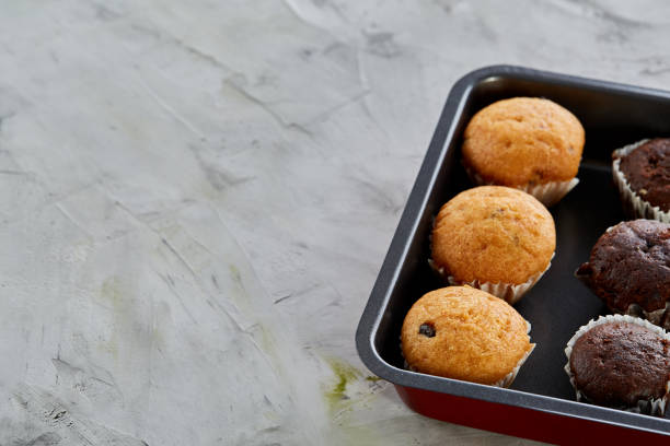 istock Fresh baked chocolate muffins on a cookie sheet, top view, close-up, selective focus 1010172866