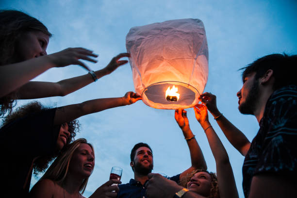istock Friends lighting up a paper lantern at party 1010179480
