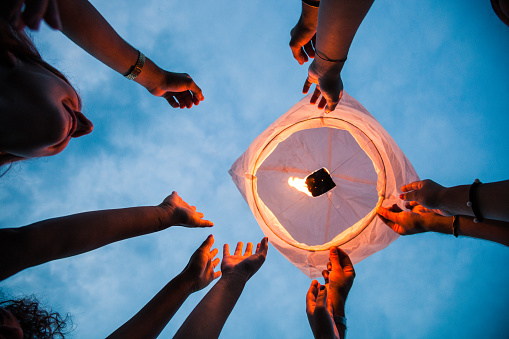 Friends lighting up a paper lantern at party