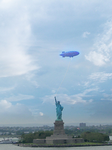 Surrealism. Liberty statue holds zeppelin on a rope.