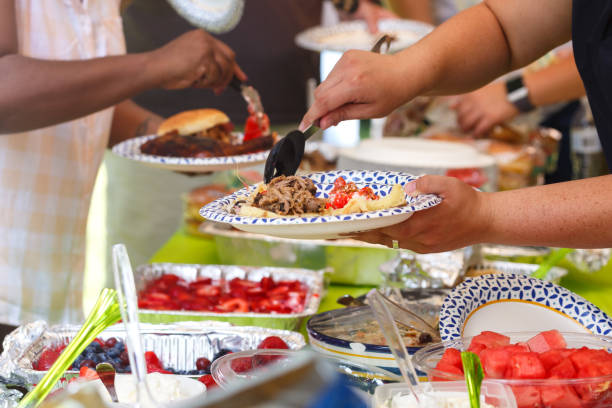 Summer Barbeque Potluck Guests filling plates at a summer cookout picnic stock pictures, royalty-free photos & images
