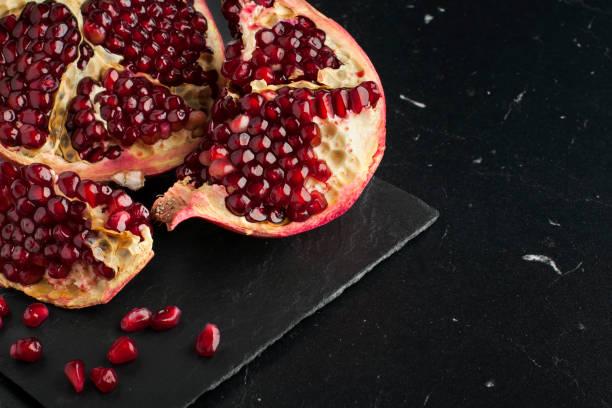 istock Juicy pieces of pomegranate on a black marble board 1010214900
