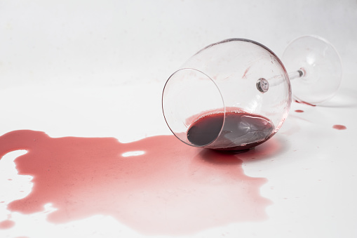 Spilled red wine out of glass on white surface