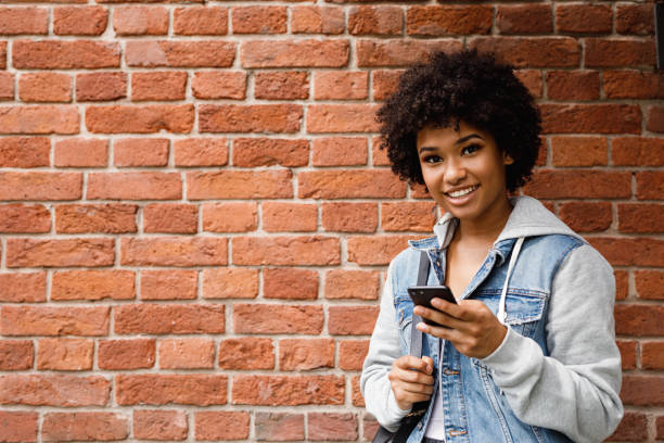 istock Smiling girl holding mobile phone, looking at camera 1010222484