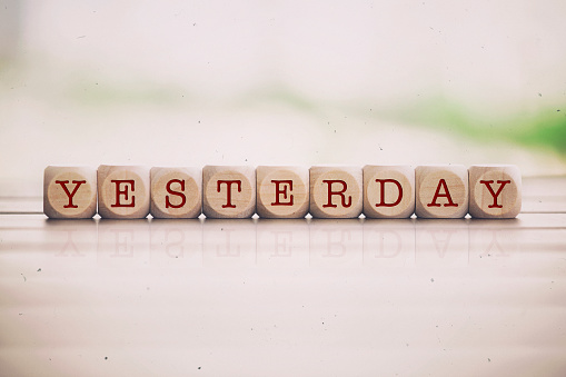 Yesterday word written on cube wooden blocks. Defocused background.