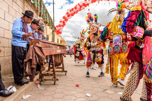 Marimba musicians & traditional folk dancers in street, Guatemala Parramos, Guatemala - December 29, 2016: Marimba musicians & traditional folk dancers in masks & costumes perform Dance of the Moors & Christians in village near Spanish colonial town & UNESCO World Heritage Site of Antigua. marimba stock pictures, royalty-free photos & images
