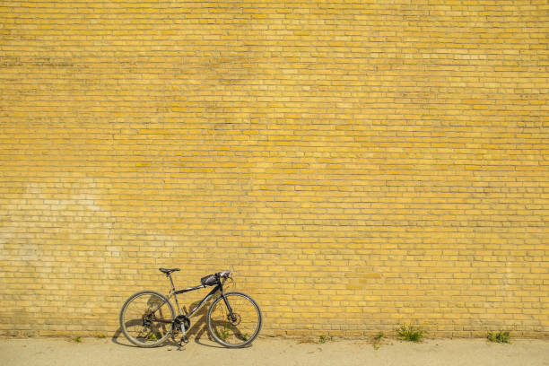 A bicycle courier checks a text from his dispatcher on his mobile phone. His bike is a one speed or fixed gear bike. His bicycle cable lock is visible inside his messenger bag.