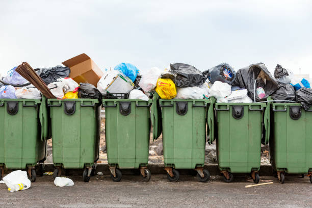 Full garbage dumpsters Many green over flowing garbage dumpsters in a row. overflowing trash dumpster stock pictures, royalty-free photos & images
