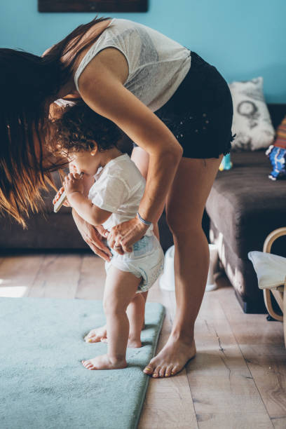 istock Mother changing diaper on toddler while standing 1010250128