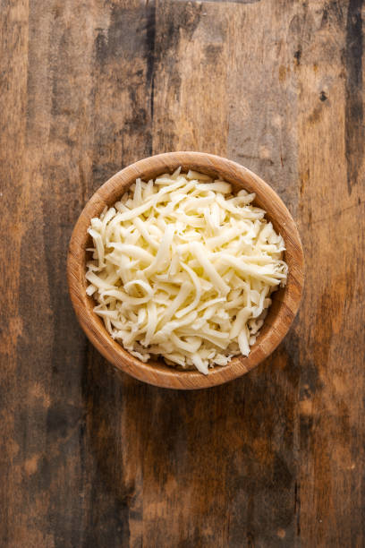 heap of grated mozzarella cheese heap of grated mozzarella cheese in wooden bowl . top view shredded mozzarella stock pictures, royalty-free photos & images