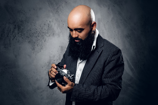 Bearded man with retro camera, studio shott. Old-fashioned clothing, retro style. Photography of the 50th.