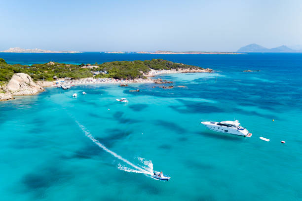 View from above, aerial view of an emerald and transparent mediterranean sea with a white beach and some boats and yachts. Costa Smeralda, Sardinia, Italy. stock photo